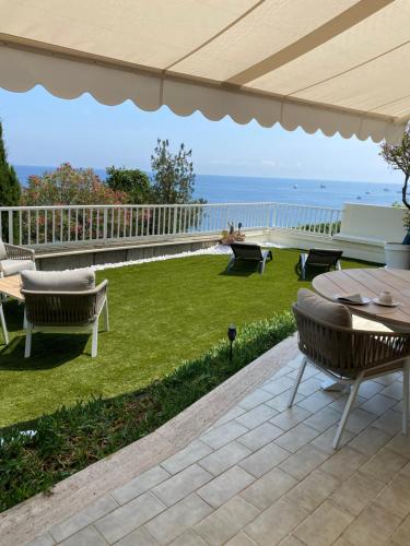 un patio con mesa, sillas y el océano en Cap d.Azur, en Roquebrune-Cap-Martin