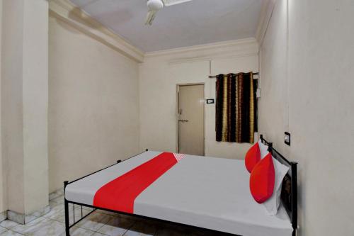 a bedroom with a white bed with red pillows at Hotel O Kr Inn in Chandrapur