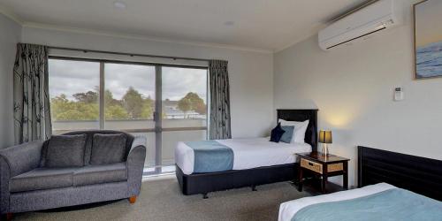 a bedroom with a bed and a chair and a window at AristaAir- Central City Townhouse in Rotorua