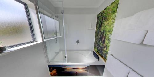 a bathroom with a bath tub and a window at AristaAir- Central City Townhouse in Rotorua