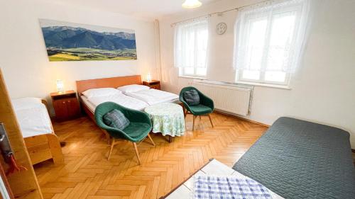 a bedroom with a bed and two green chairs at Holiday House Mária in Závažná Poruba