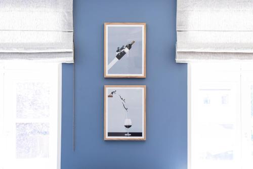 three framed pictures on a blue wall with windows at Ferienhaus im Altstadtgässchen mit 3 Badezimmern in Quedlinburg
