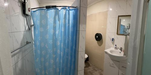 La salle de bains est pourvue d'un rideau de douche bleu et d'un lavabo. dans l'établissement Mapusagas Riverside x2Bedrooms Home away from home #4 Sleeps 2-6, à Apia