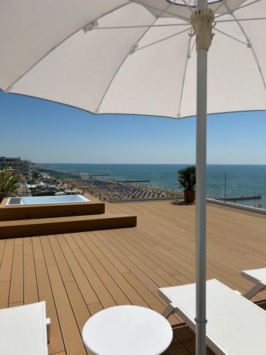 a patio with an umbrella and chairs and the ocean at Hotel Mirafiori in Lido di Jesolo