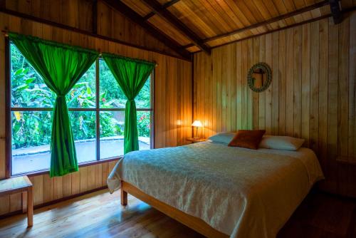 ein Schlafzimmer mit einem Bett und einem großen Fenster in der Unterkunft Mindo Lago Hotel Destino in Mindo