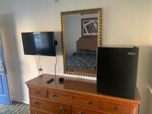 a television on top of a dresser with a mirror at Deluxe Inn Austin in Austin