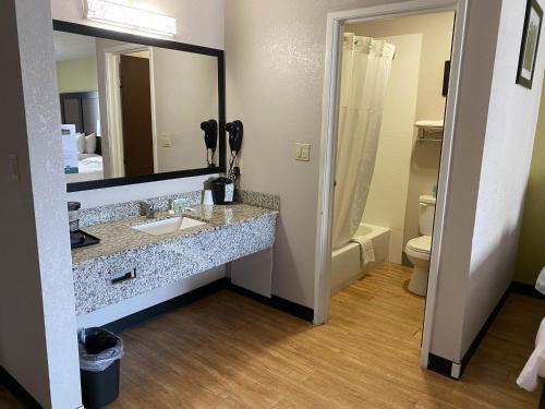 a bathroom with a sink and a mirror and a toilet at Motel 6 Lancaster in Lancaster