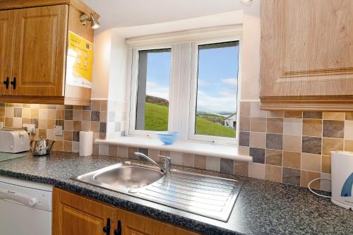 a kitchen with a sink and a window at Downings Coastguard Cottages - Type B-E in Downings