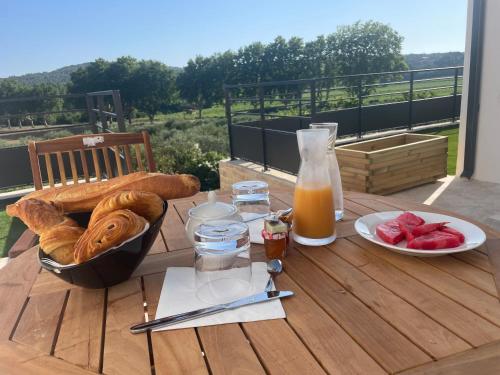a table with bread and juice and a bowl of fruit at Noyau & Pepin in Rognes