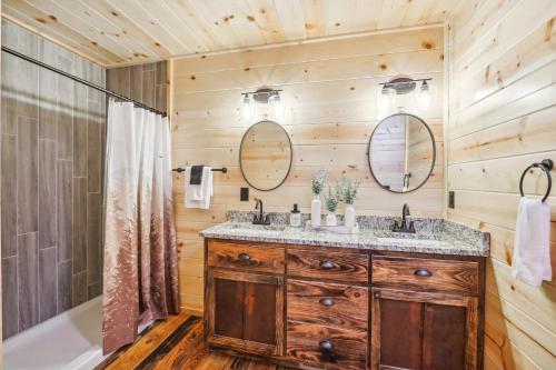 a bathroom with two sinks and a tub and a wooden wall at Private Murphy Cabin Rental with Wraparound Porch! in Murphy