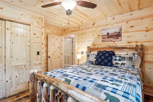 a log cabin bedroom with a bed and a ceiling fan at Private Murphy Cabin Rental with Wraparound Porch! in Murphy
