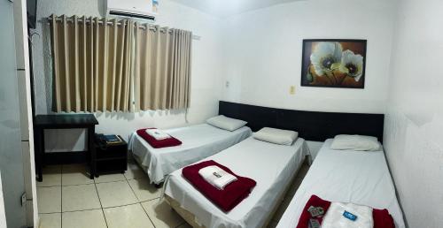 Habitación con 3 camas y una foto en la pared. en Hotel Anápolis, en Anápolis