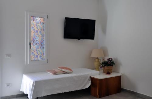 1 dormitorio con 1 cama y TV de pantalla plana en Baia delle foche, en Fertilia