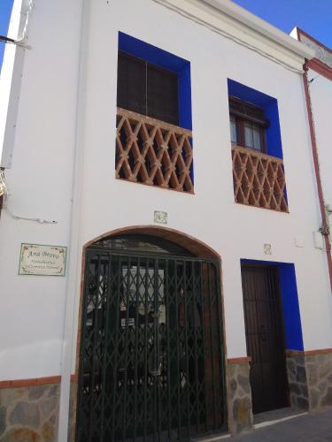 biały budynek z bramą i dwoma oknami w obiekcie El Regocijo Bajo w mieście Oliva de la Frontera