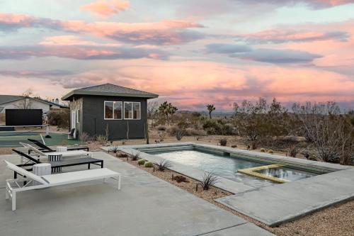 ジョシュア・ツリーにあるJoshua Tree Pool & Pickleball- Mojave Paddle Clubの椅子2脚と家のあるプール