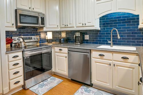 a kitchen with white cabinets and stainless steel appliances at Surfside Beach Condo with Ocean Access and Balcony! in Myrtle Beach