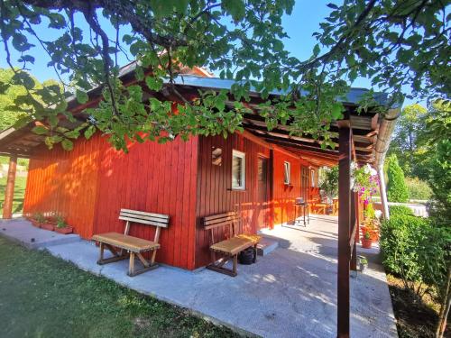 a red cabin with benches in front of it at Holiday Home La Sierra in Korenica