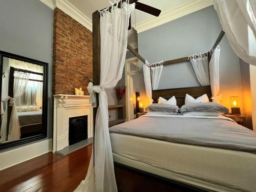 1 dormitorio con cama con dosel y chimenea en Luxury Historic Shotgun Home in Lower Garden District en Nueva Orleans