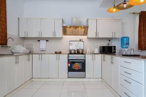 a kitchen with white cabinets and an oven at Villa Becky - Diani Beach in Diani Beach