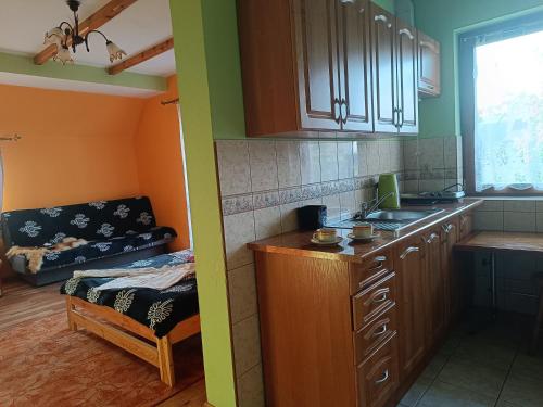 a kitchen with wooden cabinets and a couch in a room at Pokoje u Joanny in Ząb