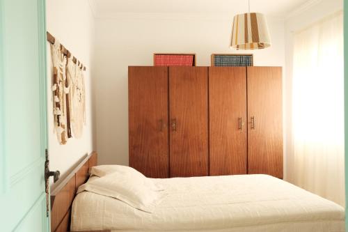 a bedroom with a bed and wooden cabinets at Furadouro Cool & Cozy Flat in Furadouro