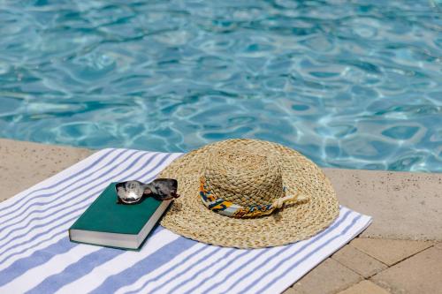 un sombrero de paja y un libro junto a una piscina en Squire Resort at the Grand Canyon, BW Signature Collection en Tusayan