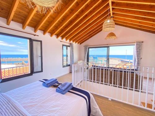 een slaapkamer met een bed en 2 grote ramen bij Casa da Baleia T2 in Vila Franca do Campo