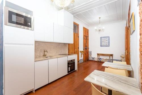 a kitchen with white cabinets and a table in a room at Historic Center romantic apartment in Lisbon