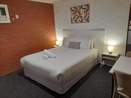 a hotel room with a bed and a red brick wall at Junction Motel Wagga in Wagga Wagga