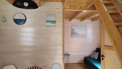 Habitación con paredes de madera y sofá azul. en Piętrowe DOMKI KLIF 6os,Cudnie Bezludnie dzika plaża łąka bociek cisza szlaki rowerowe pieski 25zl, en Debina