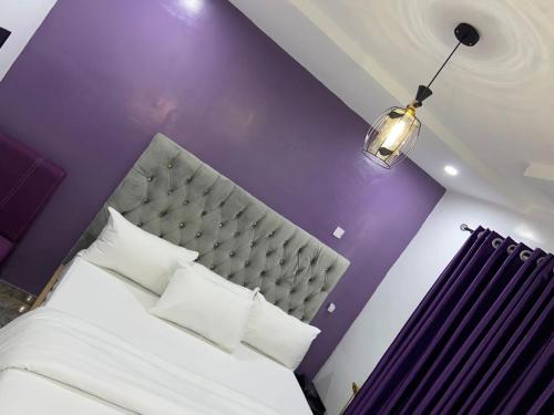 a bedroom with a white bed with a purple wall at Bamod Hotel and Suites in Lekki