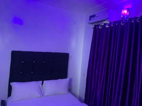 a bedroom with a bed and a purple curtain at Bamod Hotel and Suites in Lekki