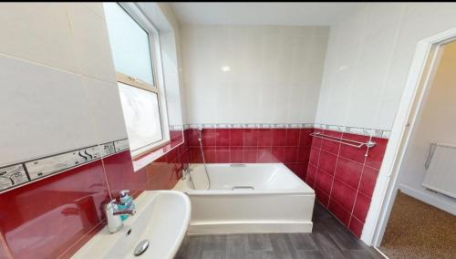 a red and white bathroom with a tub and a sink at Homely 3 Bedroom Ground Floor Flat in London