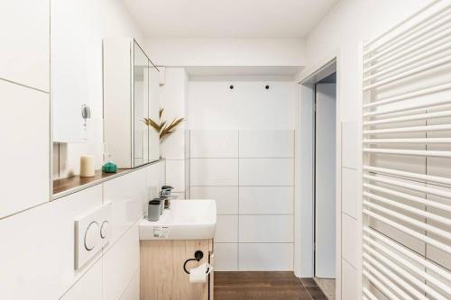 uma casa de banho branca com um lavatório e um espelho em - Heavenly apartment in the heart of Duisburg - 2 Mins Hbf Central Station - Big TV & Working space & Netflix - em Duisburg