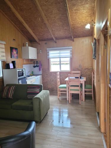 a living room with a green couch and a table at Cabañas Vientos del Sur en Puerto Puyuhuapi Aysen in Puerto Puyuhuapi