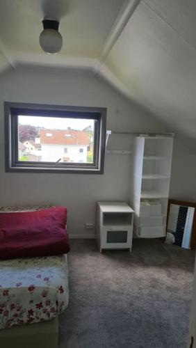 a attic bedroom with a bed and a window at Cosey 1 bedroom loft with free parking in Stavanger