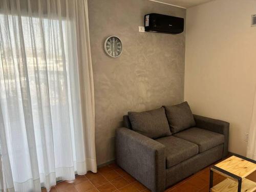 uma sala de estar com um sofá e um relógio na parede em Exclusive Urban Apartment em Mendoza