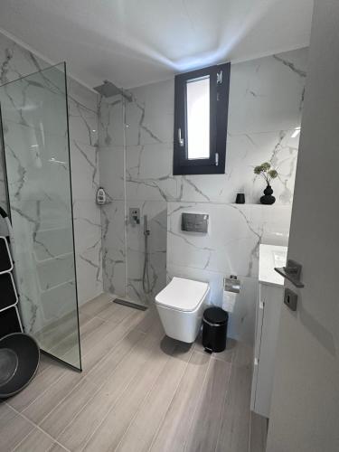 a bathroom with a toilet and a glass shower at ἕαR Exceptional Residence in Nea Peramos