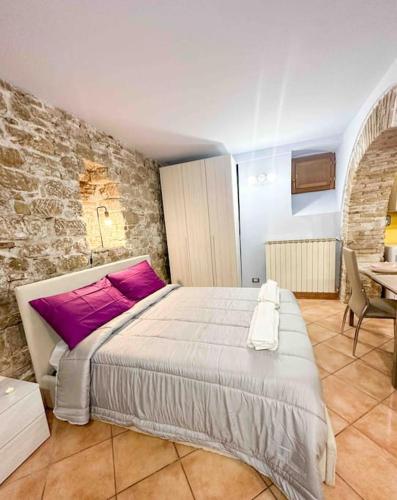 een slaapkamer met een groot bed met paarse kussens bij [Centro Storico] La casa di Pietra in Perugia