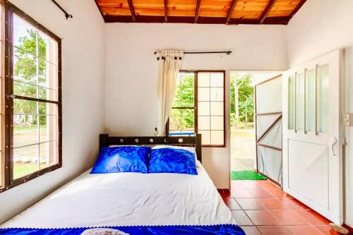 a bedroom with a bed in a room with windows at Finca Hacienda el Morichal in Villavicencio