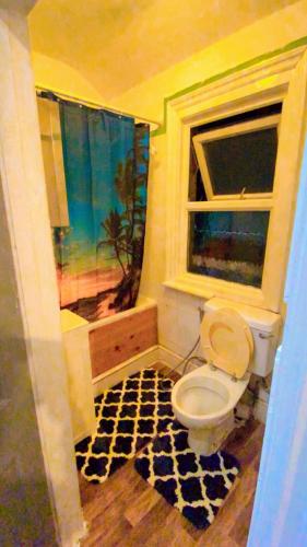 a bathroom with a toilet and a window at Home stay Rooms in Slough