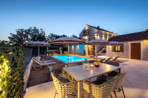 eine Terrasse mit einem Tisch und Stühlen sowie einem Pool in der Unterkunft Villa Lady Stone in Lovreć