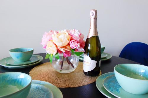 a bottle of wine and a vase of flowers on a table at Modern apartment with water view in Geelong in Geelong