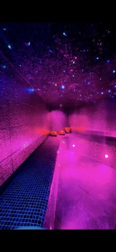 une chambre sombre avec des lumières violettes au plafond dans l'établissement Appart avec jacuzzi, et terrasse, à Marseille