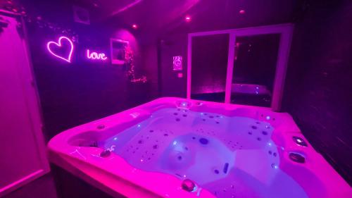 une salle de bain rose avec une baignoire avec un signe de cœur dans l'établissement Appart avec jacuzzi, et terrasse, à Marseille