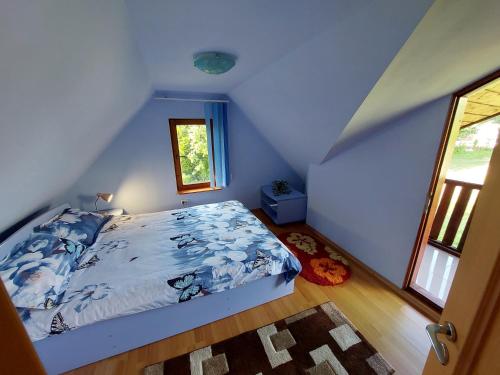 a bedroom with a bed with blue sheets and a window at Cabană cu teren de tenis -- etaj in Băniţa