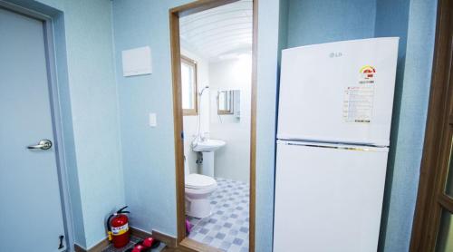 a bathroom with a white refrigerator and a toilet at Suncheon Bay Ecology Pension in Suncheon