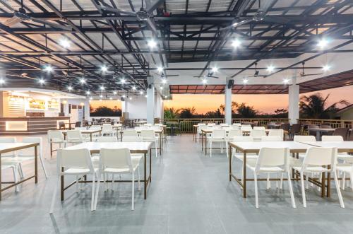 un restaurante con mesas blancas y sillas blancas en Magsaysay Hillside Resort powered by Cocotel, 