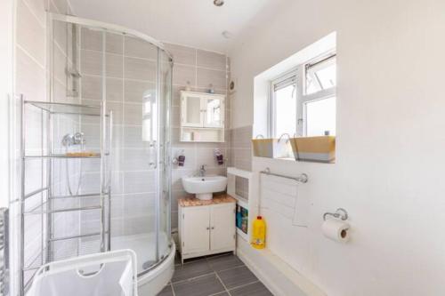 a white bathroom with a shower and a sink at cosy 1 bedroom flat near Barking town centre in Barking