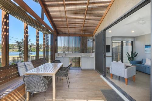 a deck with a table and chairs and a kitchen at Reflections Evans Head - Holiday Park in Evans Head